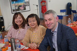 Will Forster smiling. To his right are two women, also looking at the camera and smiling